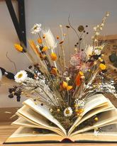 Composición de flores secas de Arrels de la Vila brotando de un libro abierto