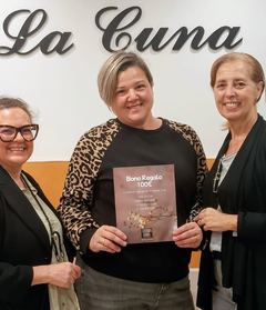 Las organizadoras entregan un vale regalo del sorteo en la tienda La Cuna, edición 2025