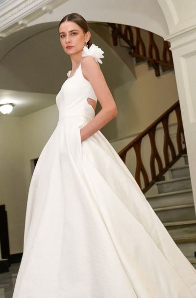 Novia con vestido de satén y espalda abierta en una escalera de arcos blancos, Celebra Gandía 2025