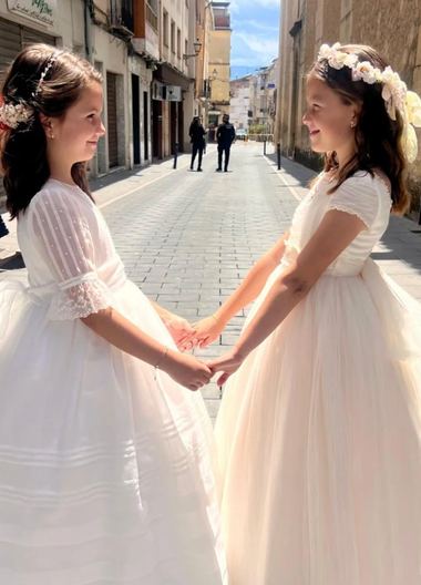 Dos niñas con vestidos de comunión de La Cuna Comuniones cogidas de la mano en una calle